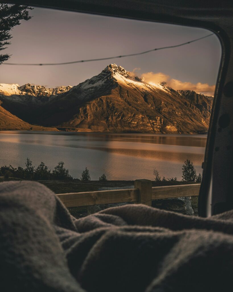 Réveil en van devant un lac et une montagne légèrement enneigée