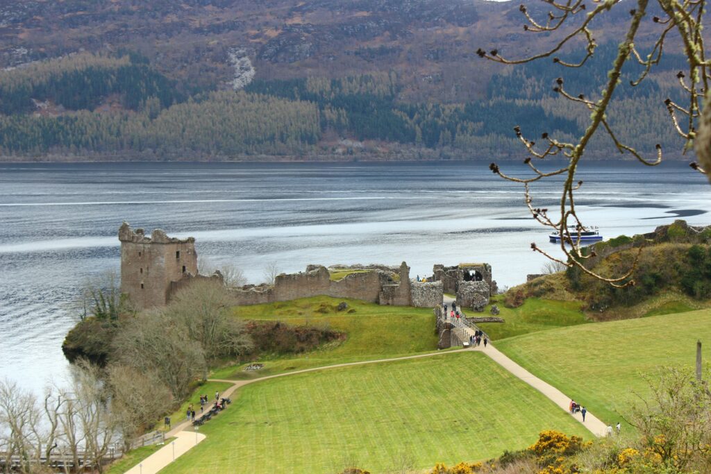 Road trip en Écosse en Van vue sur un château et un lac après une étendu d'herbe verte